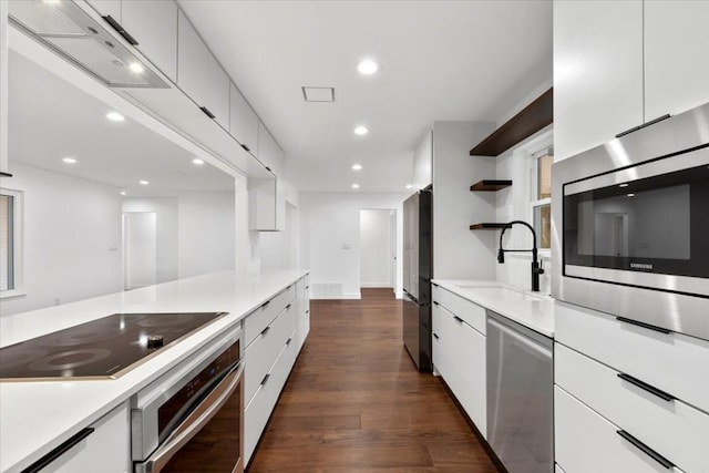 kitchen with a sink, stainless steel appliances, light countertops, and white cabinetry