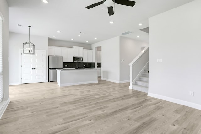 unfurnished living room with light wood finished floors, baseboards, stairway, and recessed lighting