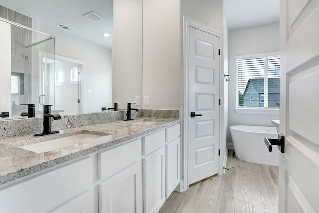 full bath with wood finished floors, a stall shower, a sink, and visible vents