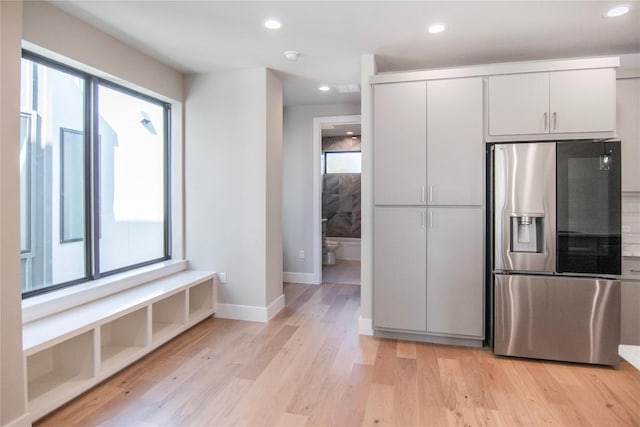 kitchen with light wood-style flooring, stainless steel refrigerator with ice dispenser, white cabinetry, and recessed lighting