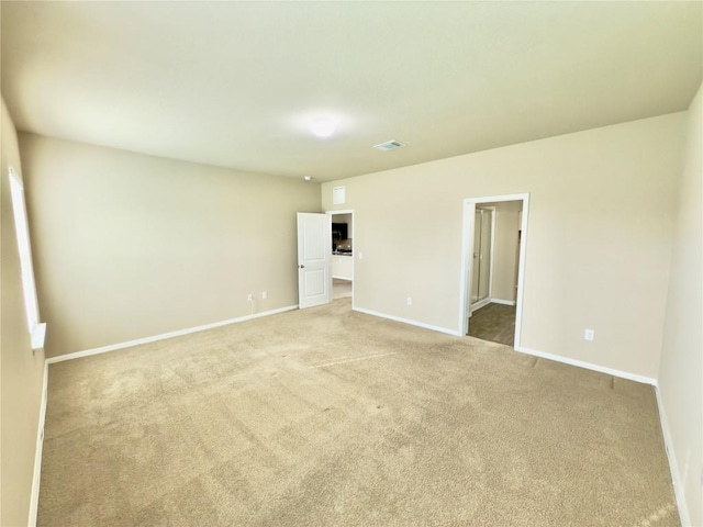 spare room featuring light carpet, visible vents, and baseboards
