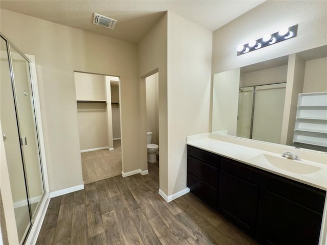 full bathroom with visible vents, a shower stall, vanity, wood finished floors, and baseboards