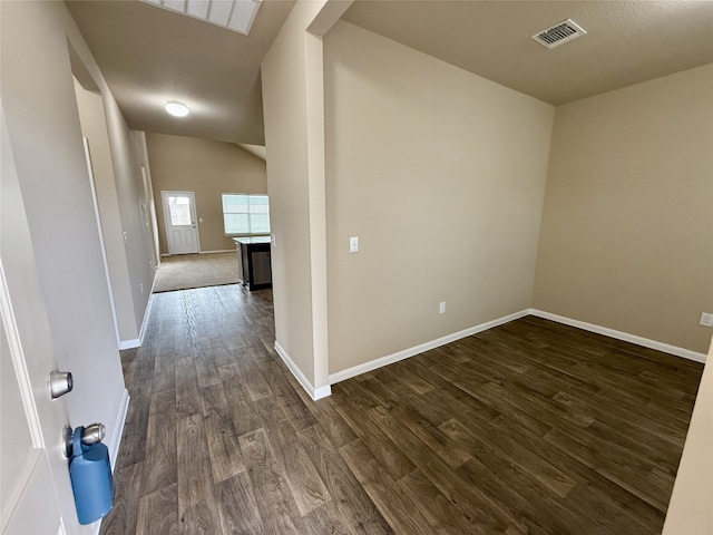 hallway with vaulted ceiling, dark wood-style flooring, visible vents, and baseboards
