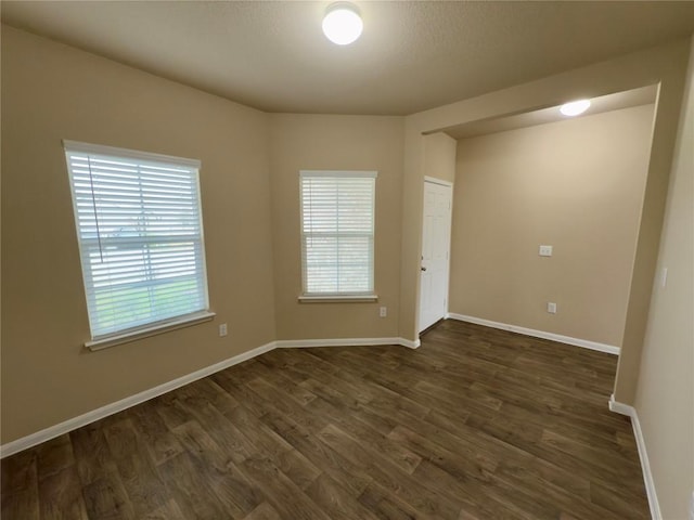 unfurnished room with dark wood finished floors and baseboards