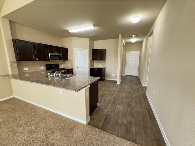 kitchen with stainless steel microwave, visible vents, dark brown cabinets, and a peninsula