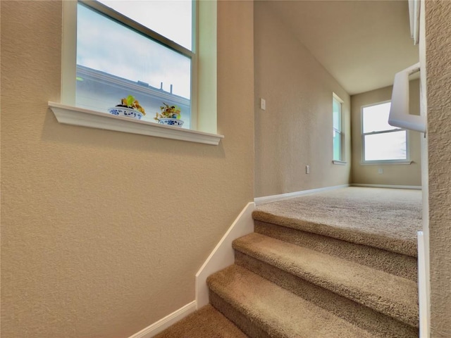 stairs featuring carpet flooring, a textured wall, and baseboards