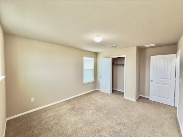 unfurnished bedroom with baseboards, visible vents, a closet, and light colored carpet