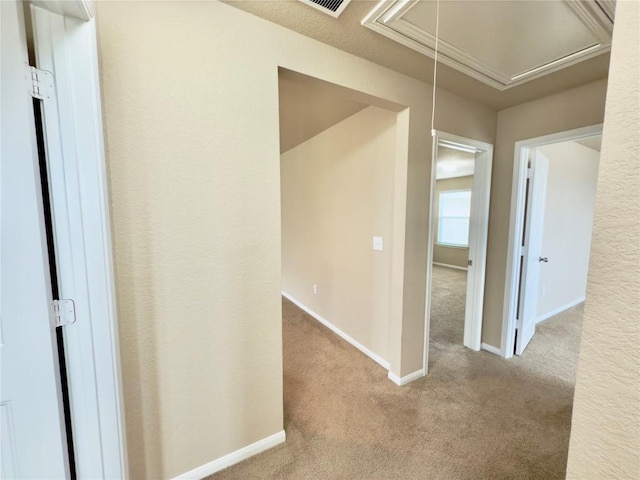 hall featuring carpet flooring, attic access, and baseboards