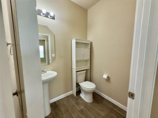 bathroom featuring a sink, wood finished floors, toilet, and baseboards