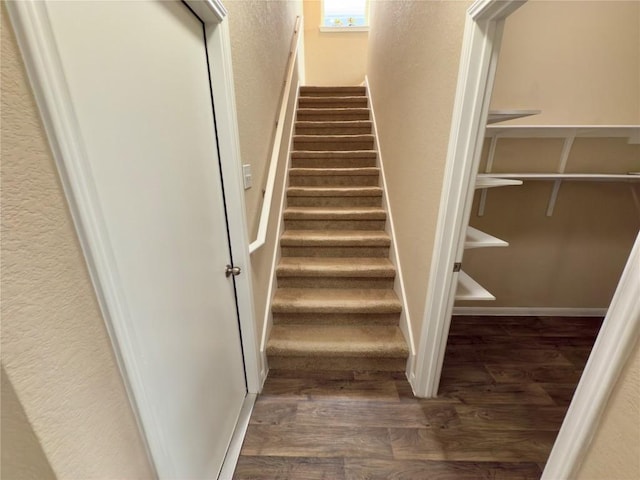 staircase featuring a textured wall and wood finished floors