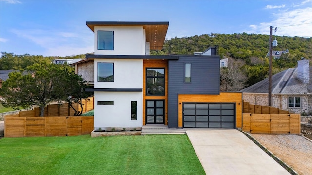 modern home featuring driveway, fence, and a front lawn