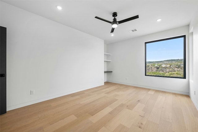 unfurnished room with a ceiling fan, visible vents, light wood-style flooring, and baseboards