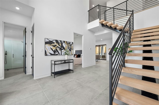 foyer entrance with recessed lighting, a towering ceiling, baseboards, and stairs