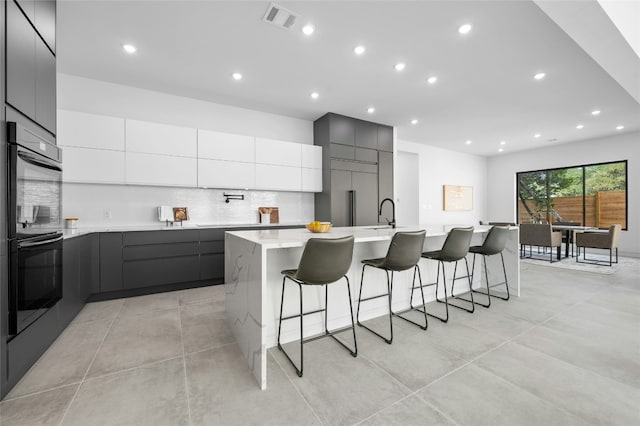 kitchen with a spacious island, light countertops, visible vents, and modern cabinets