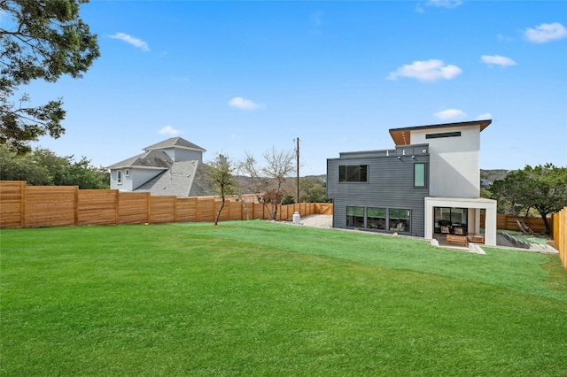 rear view of property with a fenced backyard and a lawn