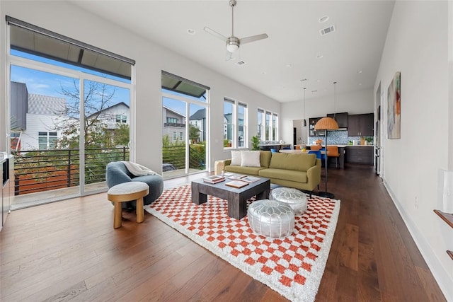 living room featuring visible vents, ceiling fan, baseboards, dark wood finished floors, and a towering ceiling