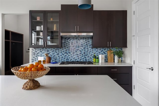 6221 Seville Dr, Austin, TX 78724 - kitchen featuring light countertops, stainless steel gas stovetop, under cabinet range hood, and dark brown cabinetry