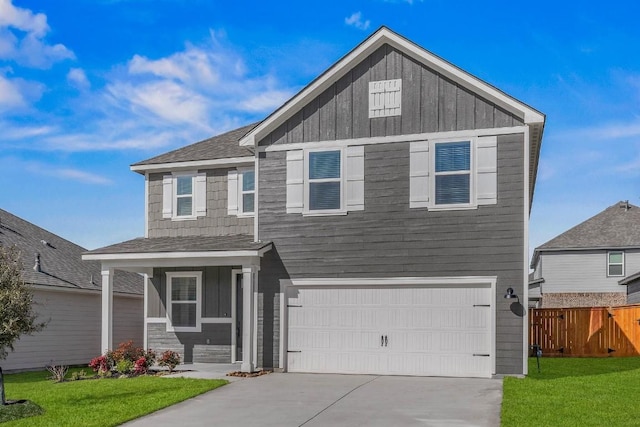 craftsman-style home with concrete driveway, an attached garage, board and batten siding, fence, and a front lawn