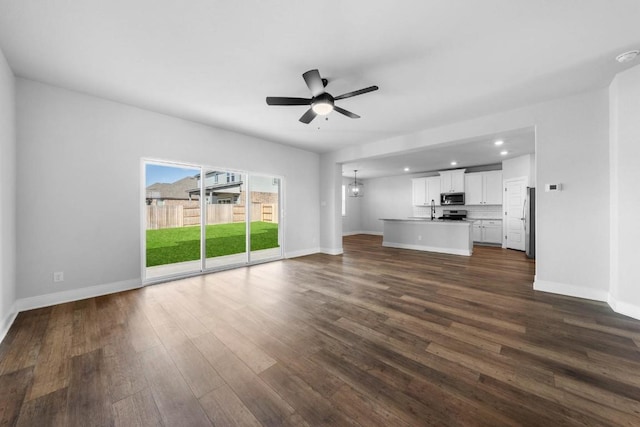 unfurnished living room featuring ceiling fan, dark wood finished floors, and baseboards