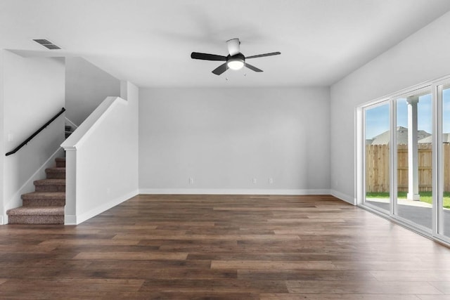 unfurnished living room with baseboards, visible vents, a ceiling fan, stairway, and dark wood-type flooring