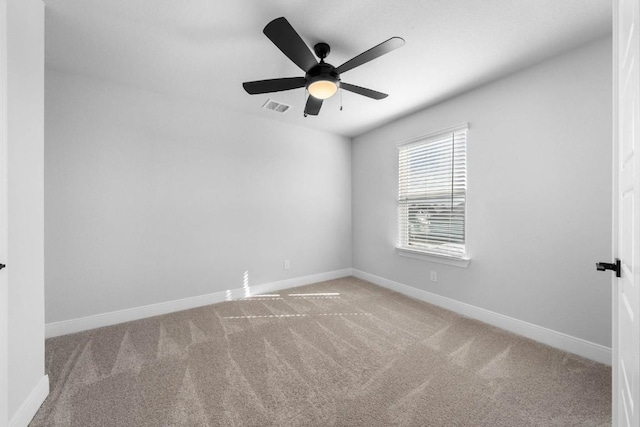 carpeted spare room with baseboards, visible vents, and ceiling fan