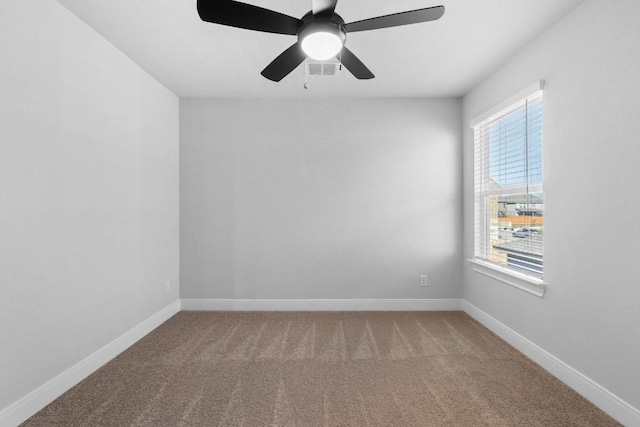 carpeted spare room featuring a ceiling fan, visible vents, and baseboards