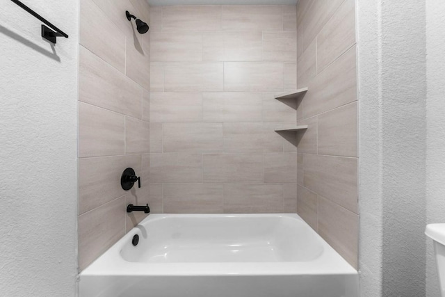 bathroom with toilet, shower / tub combination, and a textured wall