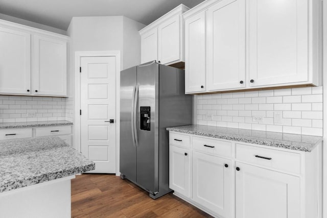 kitchen with light stone countertops, dark wood-style flooring, white cabinets, decorative backsplash, and stainless steel fridge with ice dispenser