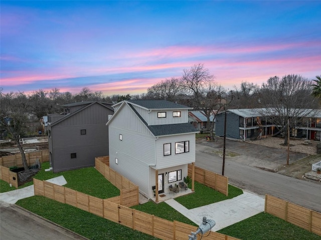 view of front of home featuring roof with shingles, a yard, a fenced front yard, and board and batten siding