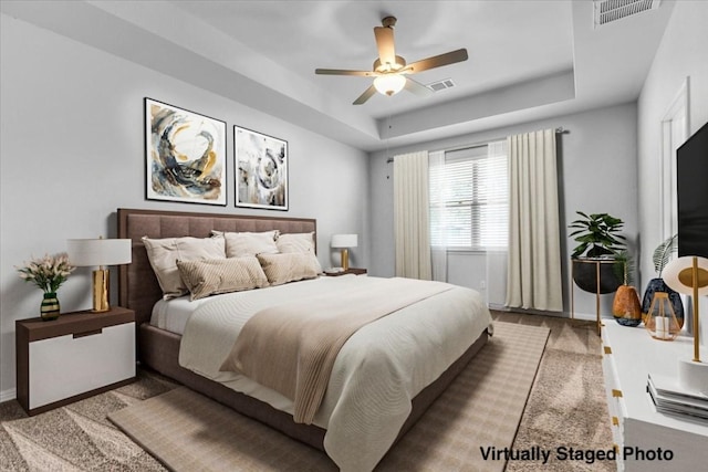 bedroom with a tray ceiling, visible vents, and baseboards