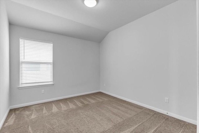 empty room with vaulted ceiling, carpet flooring, and baseboards