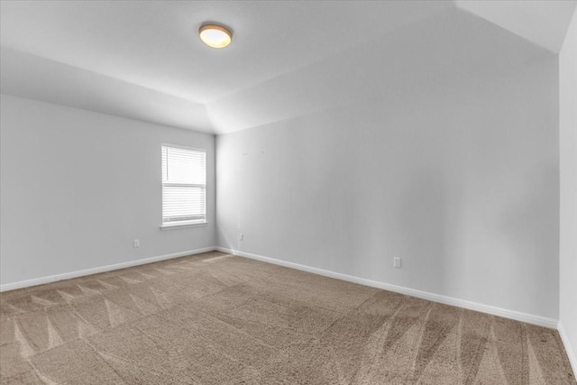 unfurnished room featuring carpet floors, vaulted ceiling, and baseboards