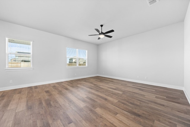 spare room with a ceiling fan, wood finished floors, visible vents, and baseboards