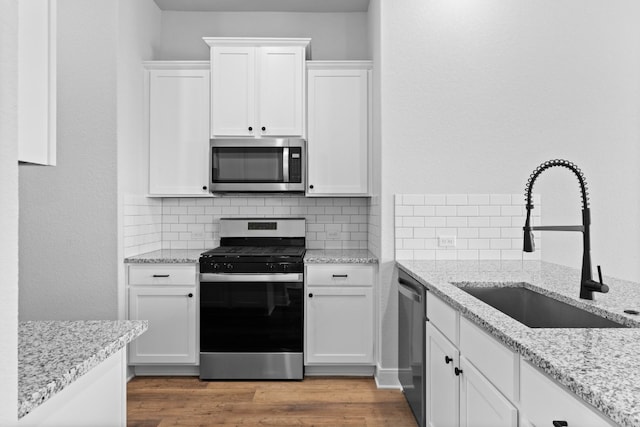 kitchen with appliances with stainless steel finishes, a sink, and white cabinets