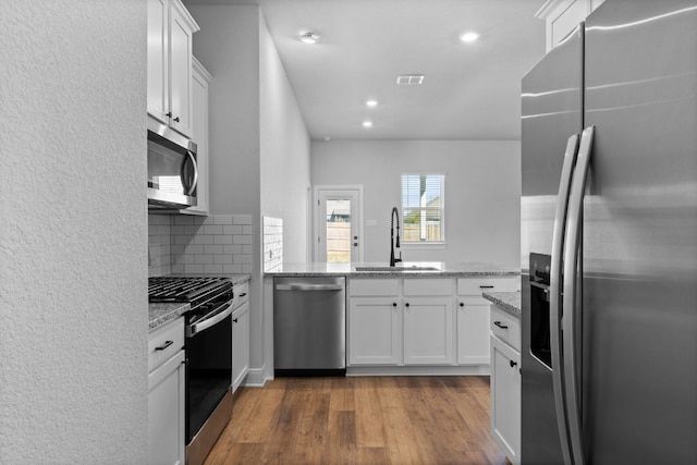 kitchen with visible vents, white cabinets, light stone counters, appliances with stainless steel finishes, and a sink