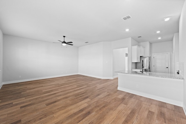 unfurnished living room with recessed lighting, visible vents, a ceiling fan, wood finished floors, and baseboards