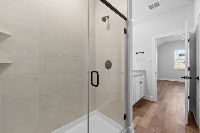 full bath featuring wood finished floors, vanity, visible vents, baseboards, and a stall shower