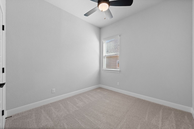 carpeted spare room featuring ceiling fan and baseboards