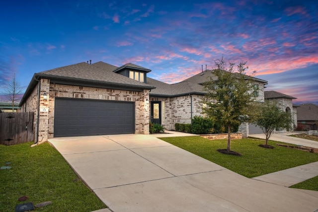 view of front facade with concrete driveway, brick siding, a yard, and an attached garage