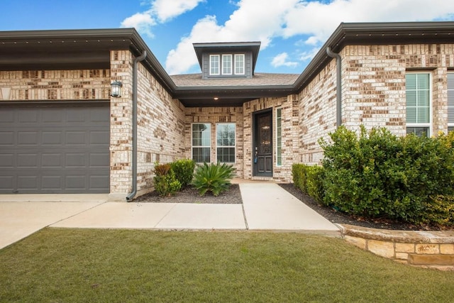 doorway to property with brick siding, a yard, and an attached garage