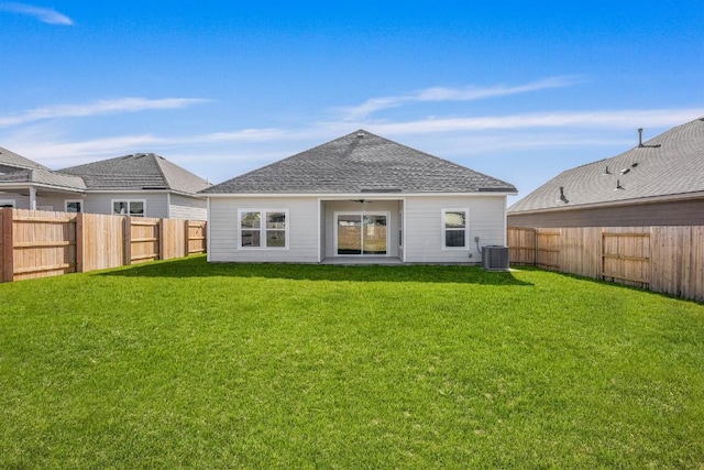 rear view of property featuring roof with shingles, a fenced backyard, a lawn, and central air condition unit