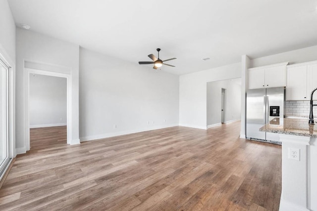 unfurnished living room featuring light wood-type flooring, ceiling fan, visible vents, and baseboards