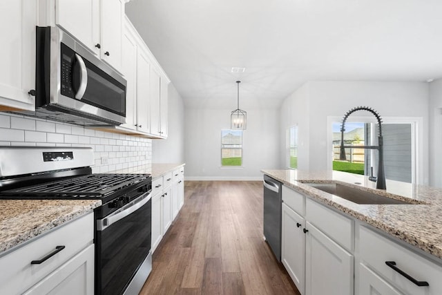 kitchen with appliances with stainless steel finishes, a sink, decorative light fixtures, and white cabinets