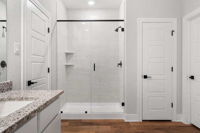 full bath with vanity, a shower stall, and wood finished floors