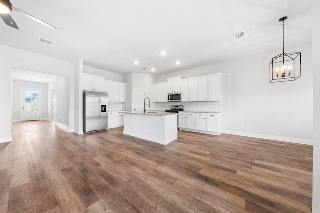 kitchen with a center island with sink, visible vents, appliances with stainless steel finishes, white cabinetry, and a sink