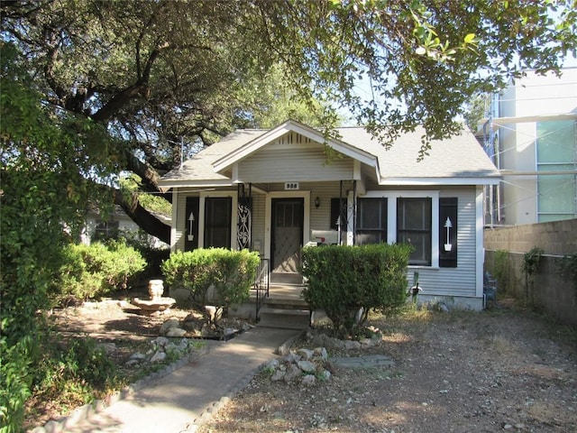 bungalow-style home with roof with shingles and fence