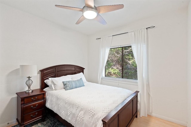 bedroom with a ceiling fan, light wood-style flooring, and baseboards