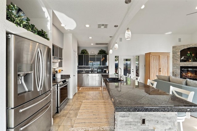 kitchen with tile countertops, visible vents, appliances with stainless steel finishes, a sink, and a kitchen breakfast bar