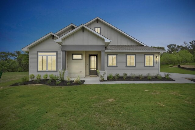 view of front facade with board and batten siding and a front lawn