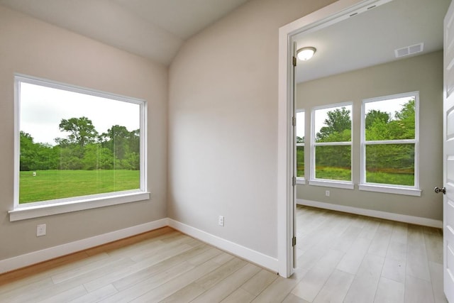 empty room with visible vents, baseboards, lofted ceiling, and light wood-type flooring